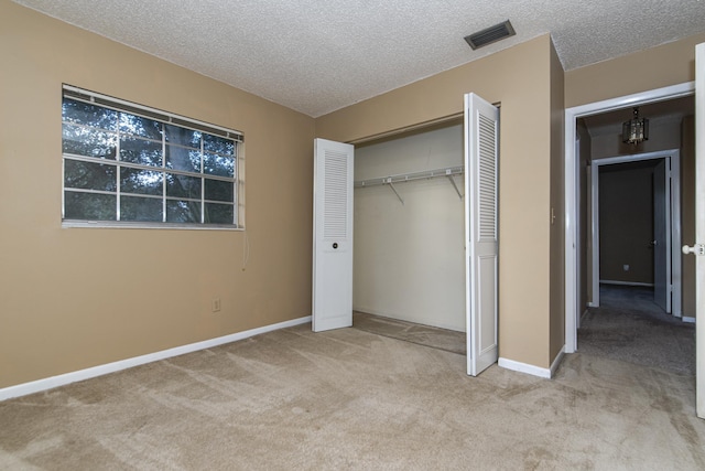 unfurnished bedroom with light colored carpet, a textured ceiling, and a closet