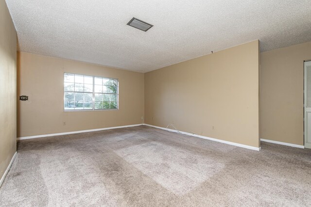 carpeted empty room featuring a textured ceiling