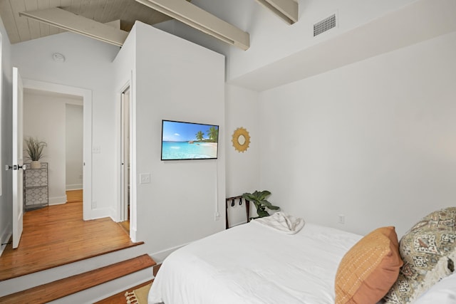 bedroom featuring hardwood / wood-style flooring and vaulted ceiling with beams