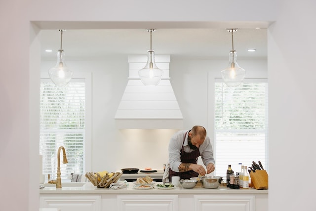 bar with pendant lighting, white cabinetry, and sink