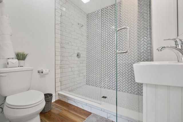 bathroom featuring sink, wood-type flooring, toilet, and a shower with door