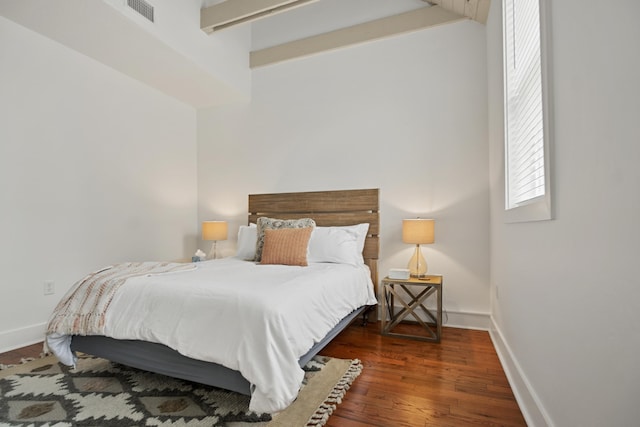 bedroom featuring dark wood-type flooring and beam ceiling