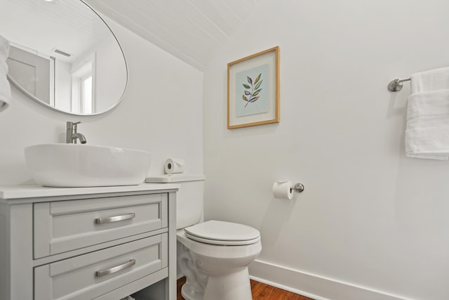 bathroom featuring hardwood / wood-style flooring, lofted ceiling, vanity, and toilet