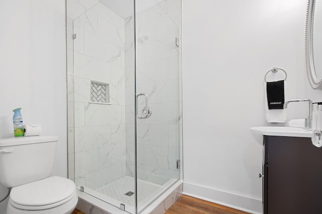 bathroom with vanity, toilet, a shower with shower door, and wood-type flooring