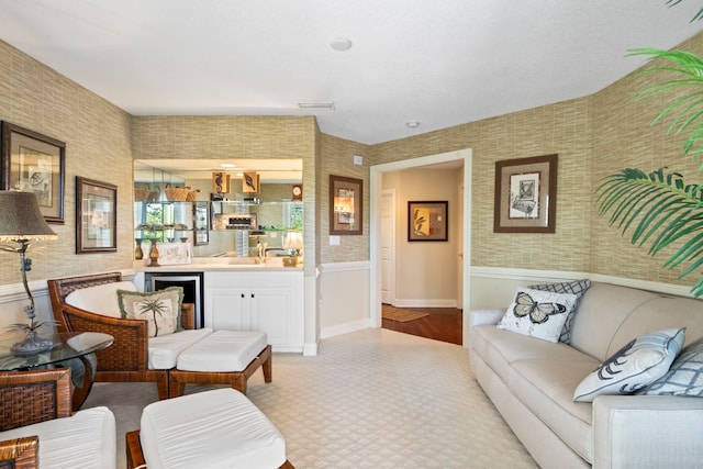 living area with wallpapered walls, a wainscoted wall, and visible vents