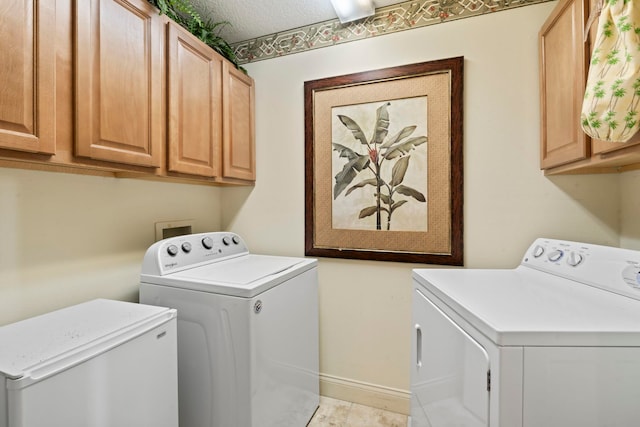 clothes washing area featuring separate washer and dryer, cabinet space, baseboards, and a textured ceiling