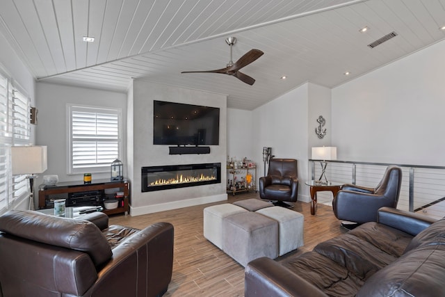 living area with a large fireplace, vaulted ceiling, wood finished floors, and visible vents