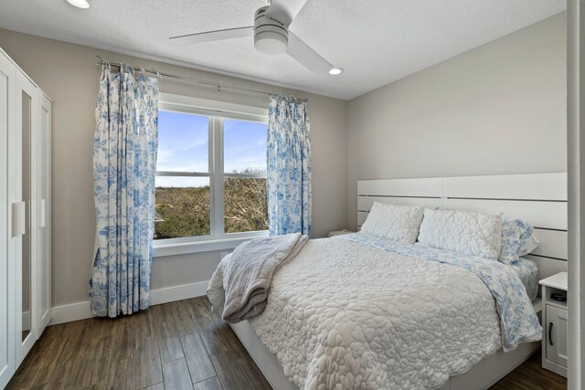 bedroom featuring a textured ceiling, baseboards, dark wood finished floors, and a ceiling fan