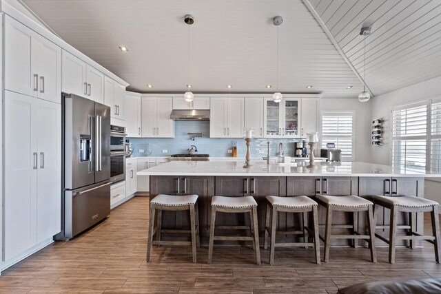 kitchen with under cabinet range hood, wood ceiling, white cabinets, appliances with stainless steel finishes, and decorative backsplash