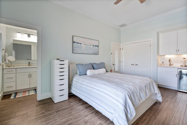 bedroom featuring baseboards, ornamental molding, wood finished floors, and ensuite bathroom