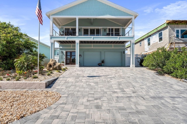 view of front of home featuring french doors, decorative driveway, an attached garage, and a balcony