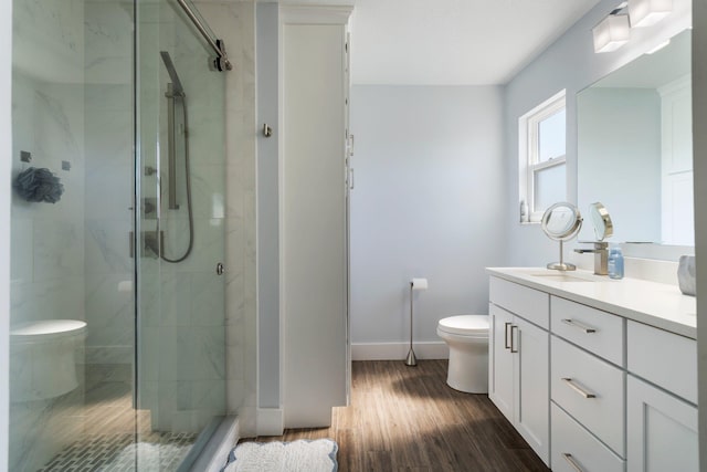 bathroom with vanity, wood finished floors, a shower stall, and toilet