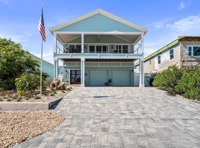 view of front of property with a balcony, an attached garage, decorative driveway, and french doors