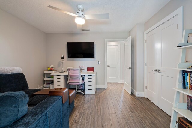 office space featuring a textured ceiling, wood finished floors, a ceiling fan, and baseboards