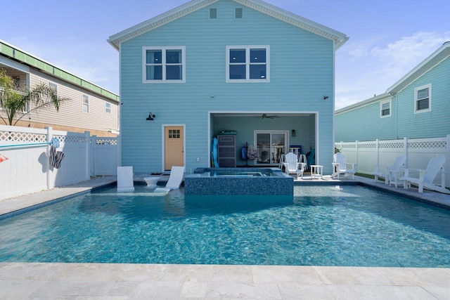 rear view of house with an in ground hot tub, a fenced backyard, a ceiling fan, and a fenced in pool