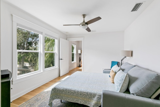 bedroom with light wood finished floors, ceiling fan, visible vents, and baseboards