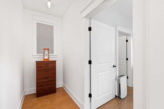 hallway featuring light wood-type flooring and baseboards