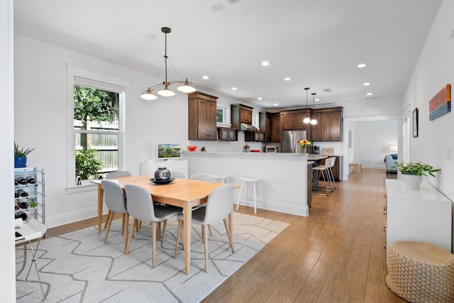 dining area featuring light wood finished floors, baseboards, and recessed lighting