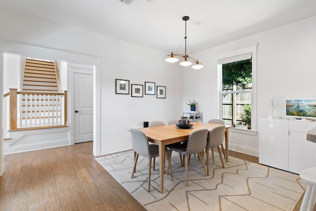 dining area with light wood-style floors, stairs, and baseboards