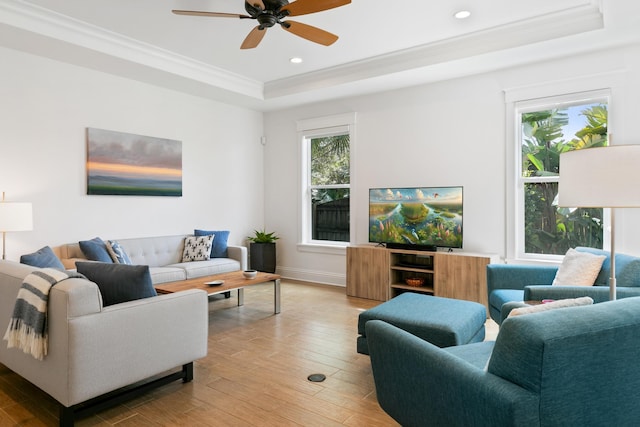 living room with baseboards, ornamental molding, a tray ceiling, light wood-type flooring, and recessed lighting