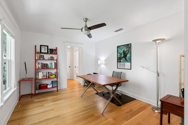 home office featuring baseboards, ceiling fan, visible vents, and light wood-style floors