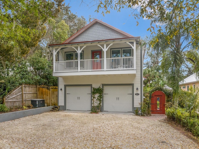 view of front of property featuring an attached garage, gravel driveway, and fence