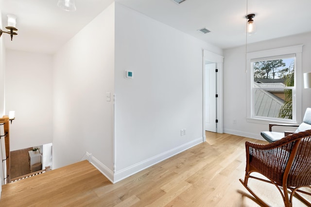 sitting room featuring light wood-style flooring, visible vents, and baseboards