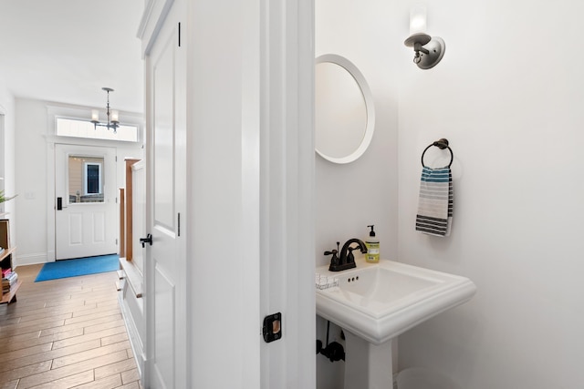 bathroom featuring a sink, baseboards, wood finished floors, and a notable chandelier