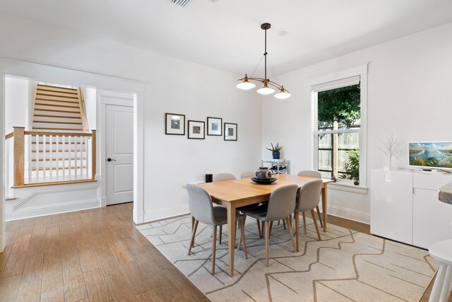 entrance foyer featuring light wood finished floors, baseboards, stairway, and a chandelier