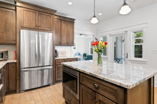 kitchen with a kitchen island, freestanding refrigerator, light wood-type flooring, black microwave, and pendant lighting