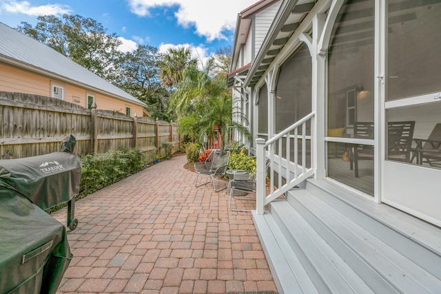 view of patio featuring a sunroom and fence