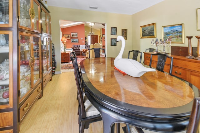 dining room featuring light wood-type flooring, visible vents, and lofted ceiling