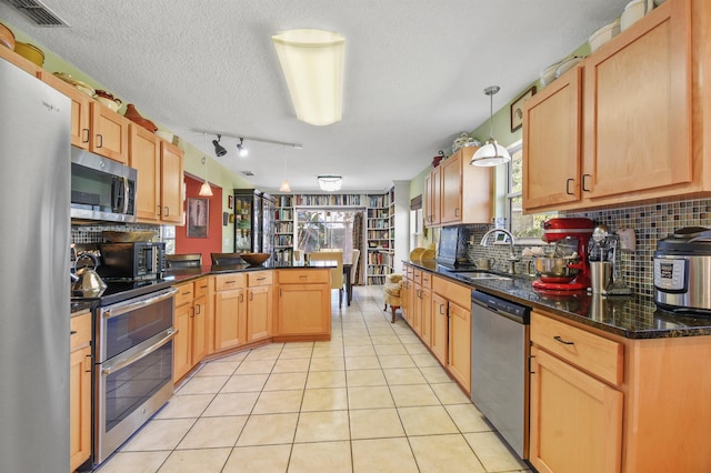 kitchen with hanging light fixtures, appliances with stainless steel finishes, light tile patterned flooring, a sink, and a peninsula