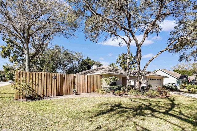 view of front facade with a garage, fence, a front lawn, and stucco siding