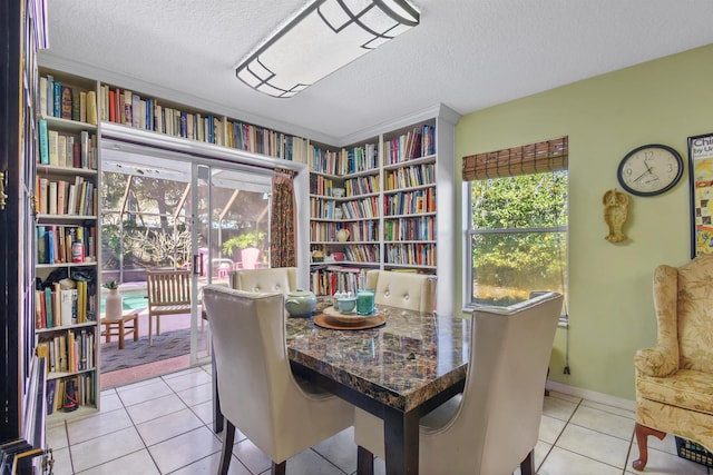 dining room featuring a textured ceiling, light tile patterned flooring, and baseboards