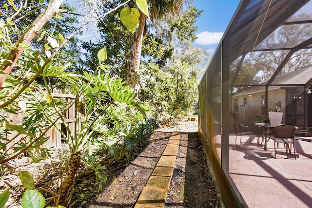 view of yard with a patio, fence, and glass enclosure