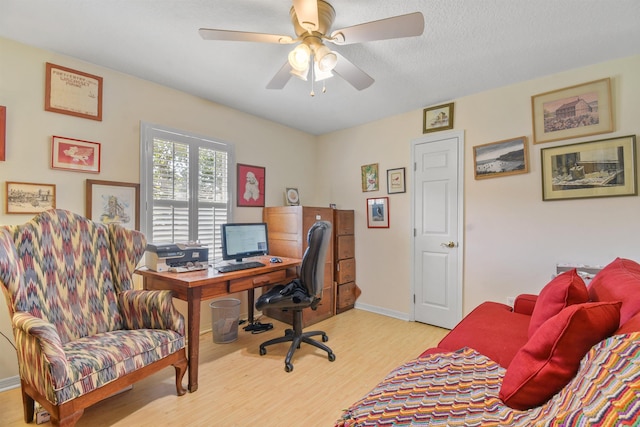 office area featuring light wood-style flooring, baseboards, ceiling fan, and a textured ceiling