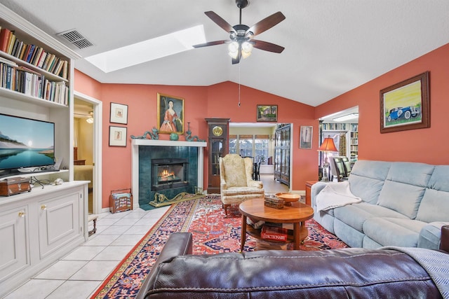 living room featuring visible vents, a tiled fireplace, lofted ceiling, ceiling fan, and light tile patterned flooring