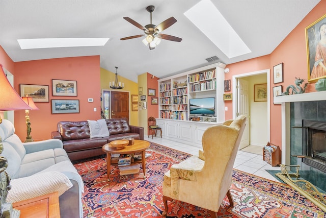 tiled living room featuring vaulted ceiling with skylight, a tiled fireplace, visible vents, and a ceiling fan