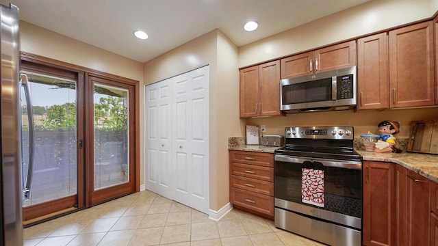 kitchen featuring light stone counters, light tile patterned floors, and stainless steel appliances