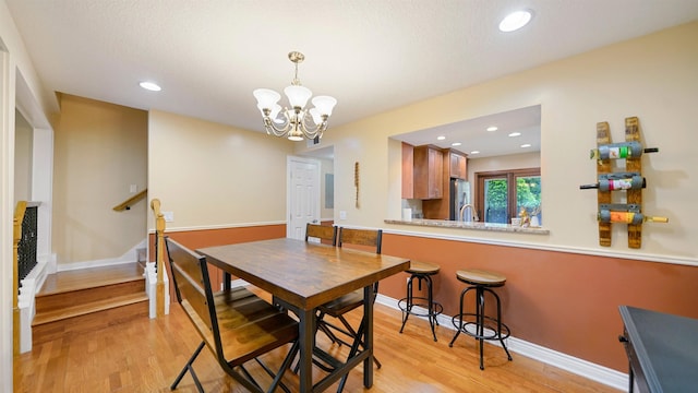 dining space with light hardwood / wood-style flooring and an inviting chandelier