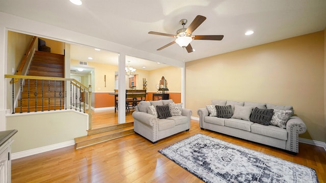 living room with wood-type flooring and ceiling fan with notable chandelier