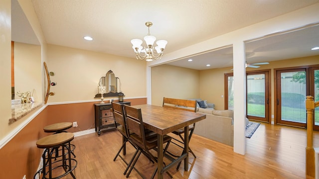 dining space featuring light hardwood / wood-style flooring and ceiling fan with notable chandelier