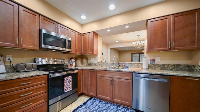 kitchen featuring light tile patterned flooring, appliances with stainless steel finishes, light stone counters, and sink