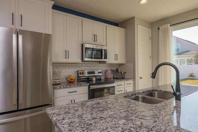 kitchen featuring white cabinetry, tasteful backsplash, appliances with stainless steel finishes, and a sink