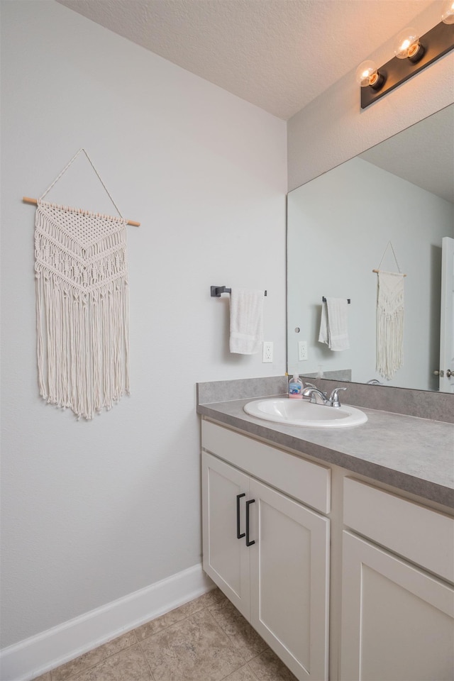 bathroom featuring a textured ceiling, baseboards, vanity, and tile patterned floors