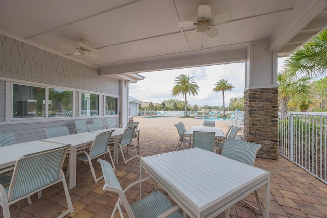 view of patio featuring a ceiling fan, outdoor dining space, and a community pool