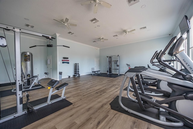 exercise room with ornamental molding, visible vents, and wood finished floors