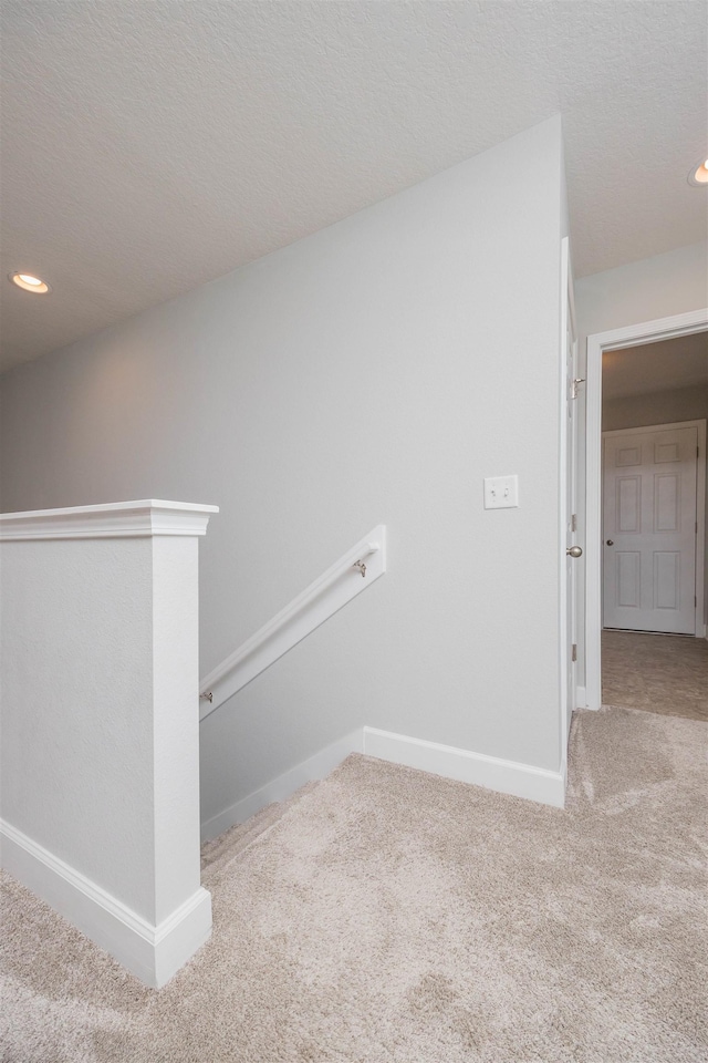 staircase with a textured ceiling, recessed lighting, carpet flooring, and baseboards