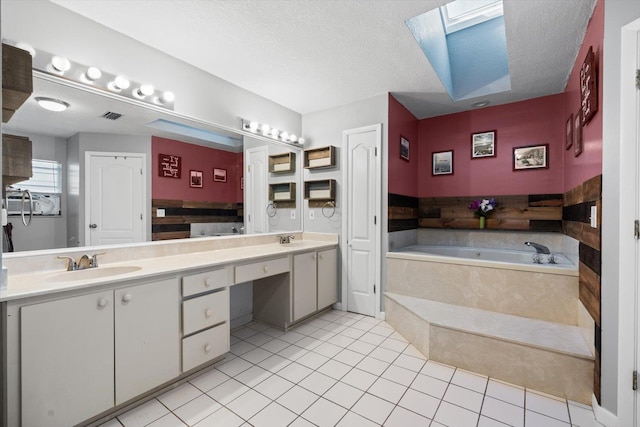 bathroom with a skylight, a relaxing tiled tub, tile patterned floors, a textured ceiling, and vanity